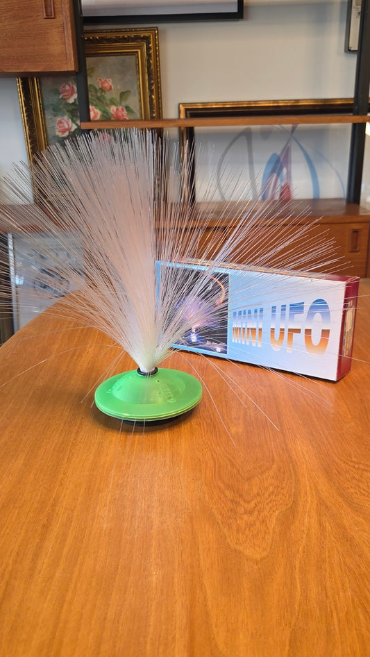 Mini UFO -kuituvalaisin vihreällä jalustalla ja pakkaus
